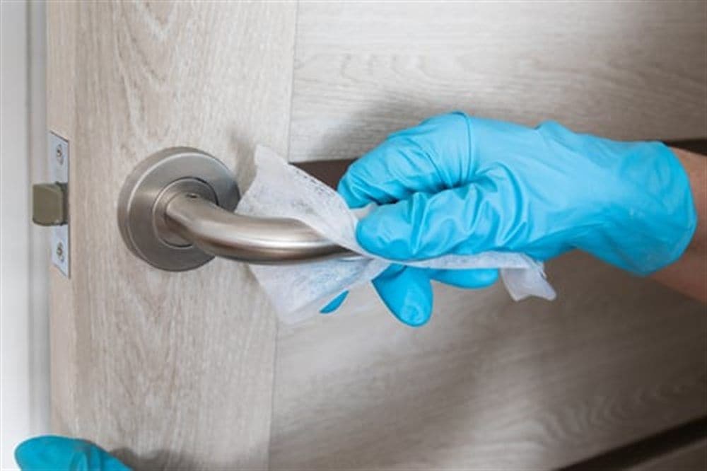 Gloved hand disinfecting a door handle during AHC commercial disinfection service